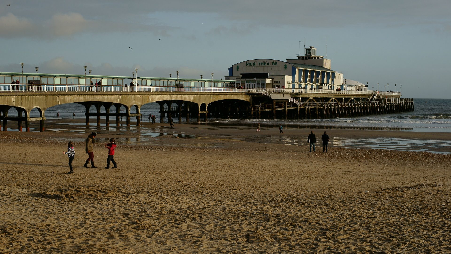 Bournemouth Pier from the sand, walkers along the water
